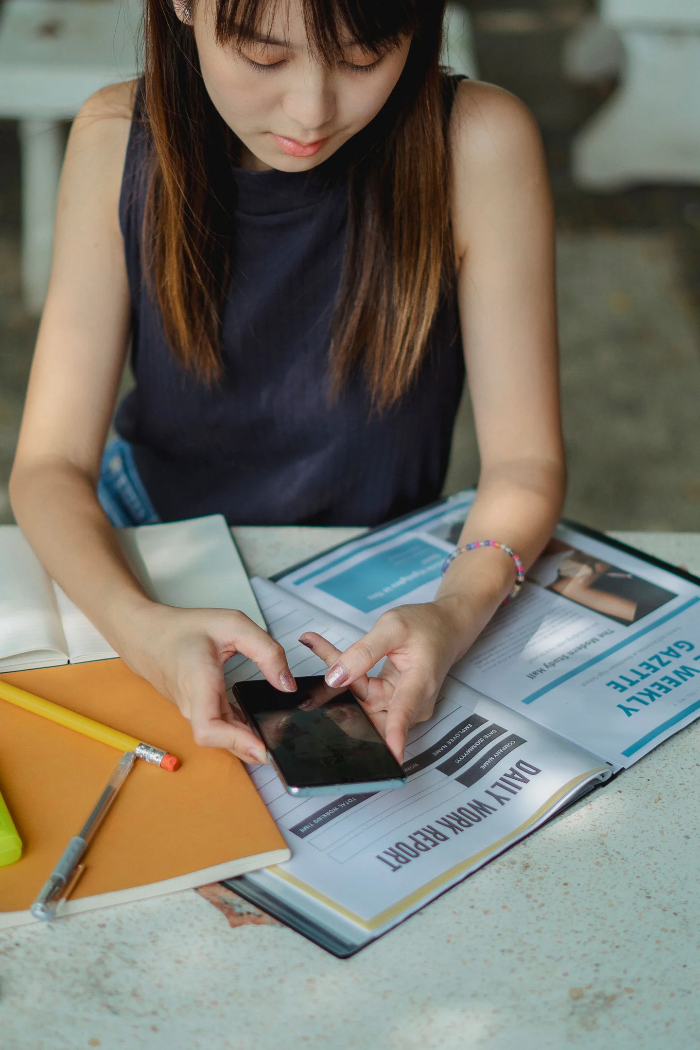 A woman checking her phone beside books